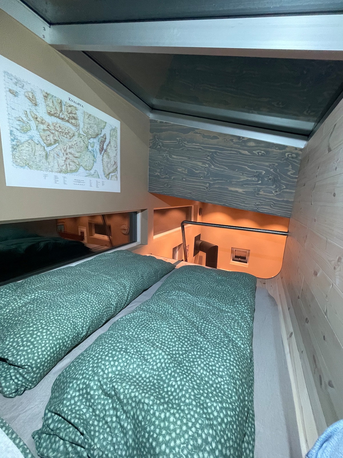 Le lit est dans le loft et il est accessible par l'escalier.
Avec une carte sur le mur au-dessus de Kvaløya pour la planification du voyage. 