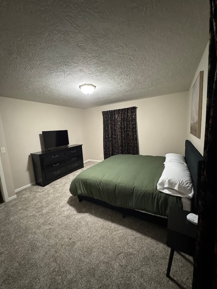 Cama tamaño king con área de armario, acceso al cargador de teléfono y TV inteligente de 43 pulgadas. 