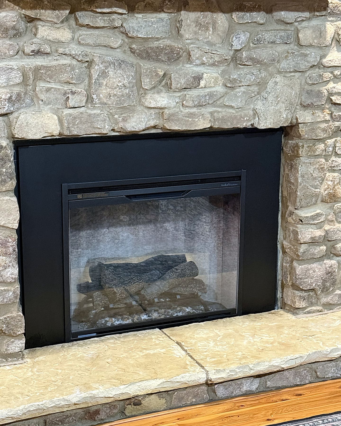 The living room's stone fireplace, now fitted with a new electric insert. No wood to haul, no smoke, and no cleanup: jus