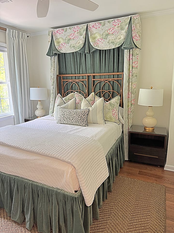 Este es un dormitorio clásico de inspiración sureña con detalles elegantes. El dosel floral y de terciopelo crea un punto focal espectacular, mientras que los cojines en capas y la ropa de cama blanca y fresca añaden textura y encanto. 