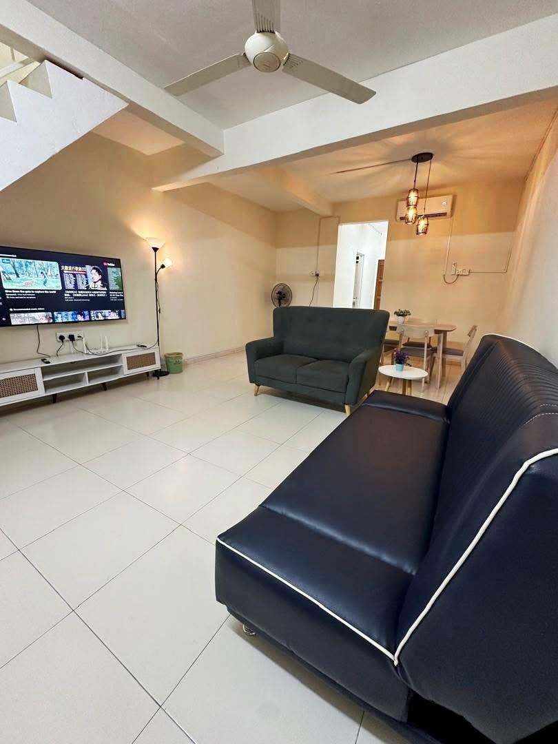 The image features a well-lit living area with a comfortable dark sofa and an elegant TV setup, including a large screen. A stylish dining table for six is visible in the background, accompanied by soft lighting that enhances the space.