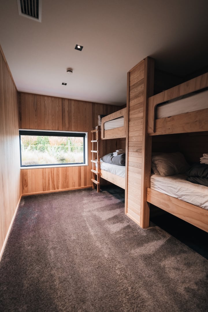 La chambre à lits superposés comprend quatre lits superposés en bois sur mesure, créant un espace chaleureux et confortable pour les enfants ou les groupes. Avec sa literie moelleuse, ses finitions en bois naturel et son ambiance de chalet, il est à la fois pratique et accueillant après une journée d'exploration.