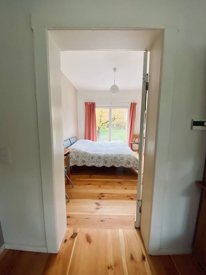 Schlafzimmer 1 im Erdgeschoss mit Zugang zum Wohn-Essbereich und Blick in den Garten. 
Bettgröße 180x200 cm, Arbeitsplatz und Kleiderschrank