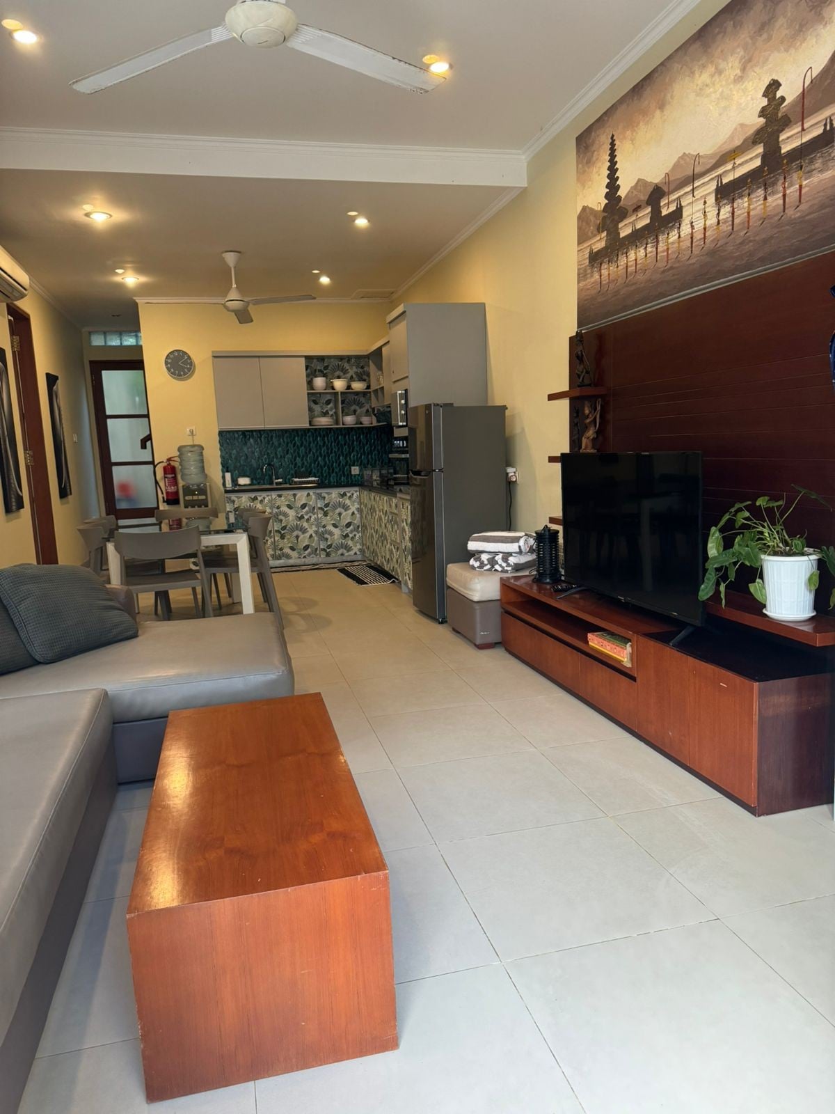 Salon, canapé avec télévision et cuisine.