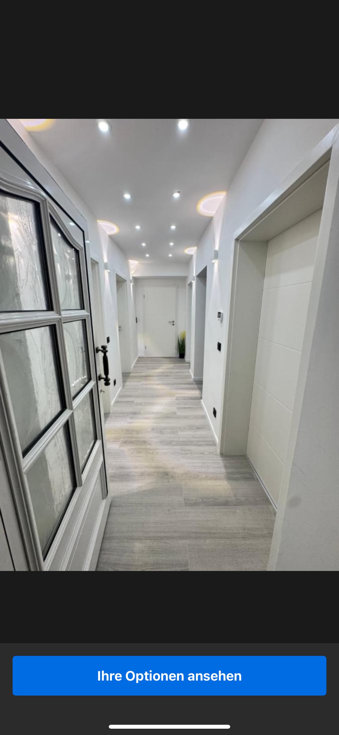 A bright hallway is illuminated by recessed lighting, featuring smooth light-colored flooring. The walls are painted in a crisp white tone, enhancing the spacious feel. Several doors line the corridor, leading to different rooms within the villa.