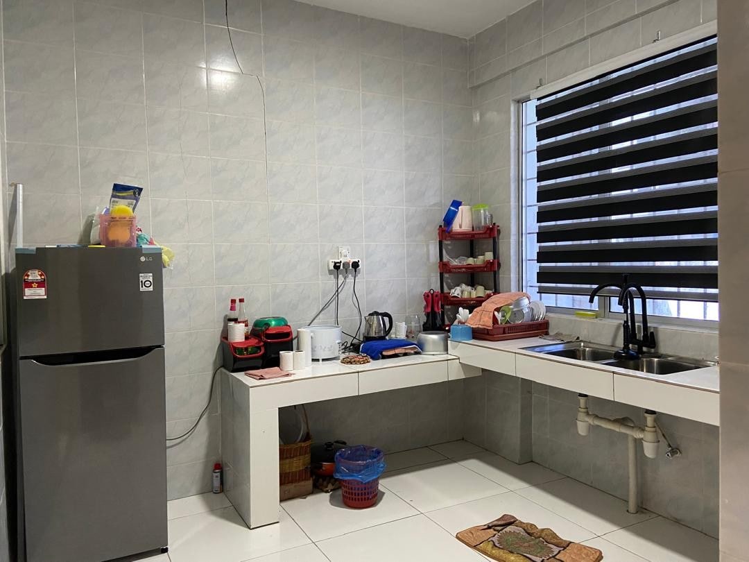 A functional kitchen is equipped with a refrigerator, sink, and ample counter space. Shelves hold various kitchenware, and a kettle is visible among other appliances. Natural light streams through a window with dark blinds, enhancing the bright tiled floor.