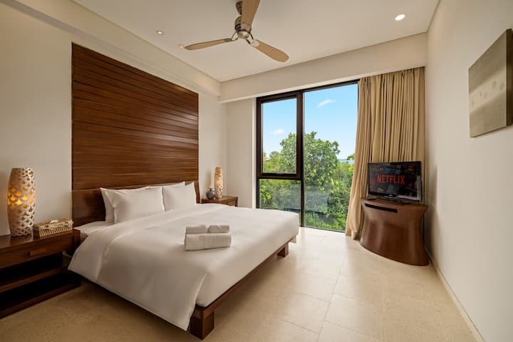 חדר השינה השני מקבל אתכם בפשטות שקטה - עץ חם, מצעים נקיים ואור טבעי רך שמסונן דרך הווילונות. מושלם ללילות נינוחים ולבקרים עצלים.