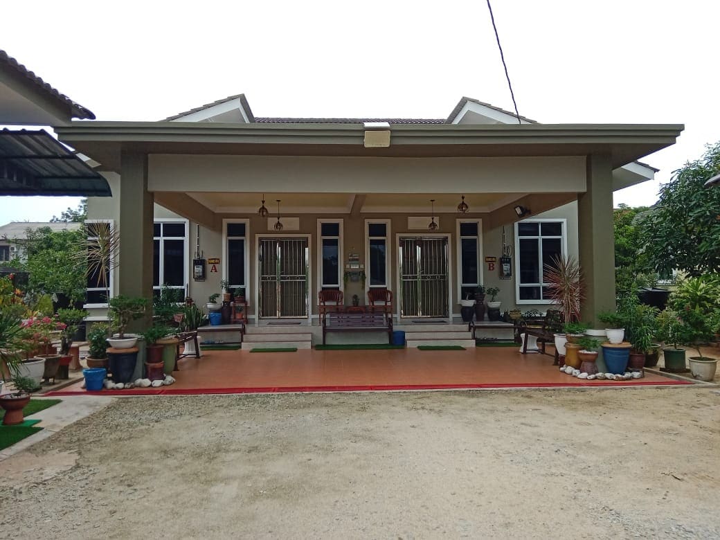The exterior of the property features a covered entrance with a spacious porch. Potted plants line the entrance, enhancing the natural surroundings. Two sets of double doors provide access to the main building, with large windows allowing natural light to fill the interior.