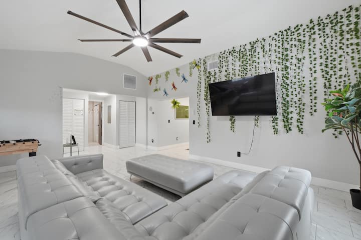 Sallon i ndritshëm modern me divan të madh modular, televizor të madh dhe mur elegant me bimësi