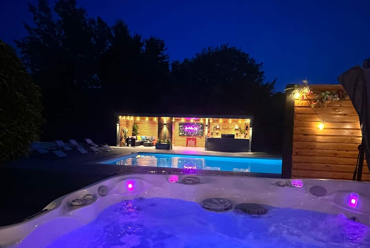 Illuminated private hot tub and swimming pool at Ingleby Retreat in the evening