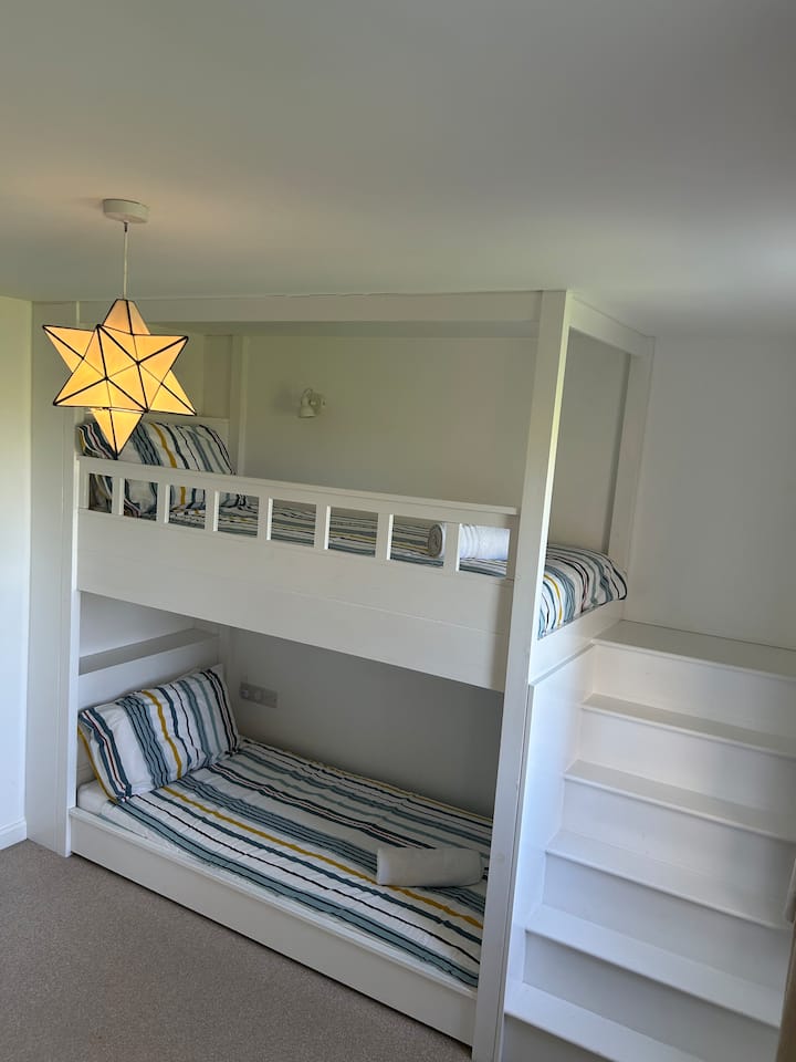 أسرة مفردة كاملة الحجم مرتبة في شكل سرير بطابقين، مع تلفزيون