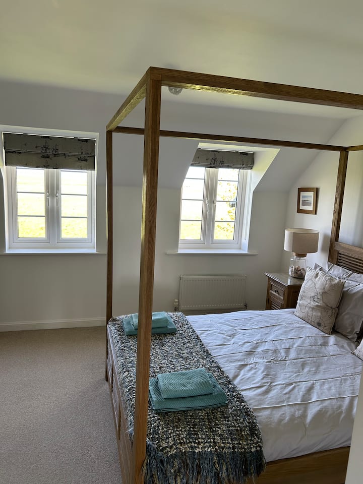 سرير كبير بحجم كينج بأربعة أعمدة يوفر إطلالات ريفية جميلة دون عائق 