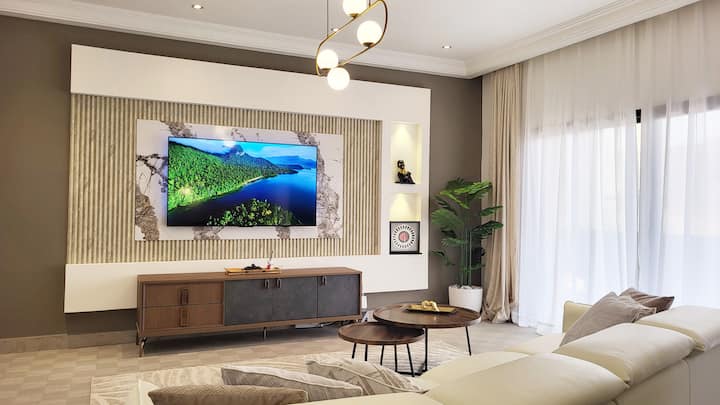 Obrovská a svetlá obývacia izba s triezvou a relaxačnou výzdobou - Pohodlná luxusná pohovka - Veľká 65-palcová inteligentná televízna obrazovka - vysokorýchlostné Wi-Fi pripojenie