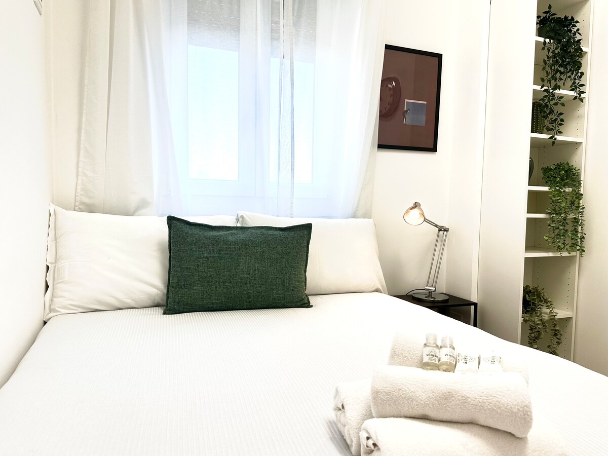 Segundo dormitorio con cama francesa, armario, espejo y persianas oscuras.