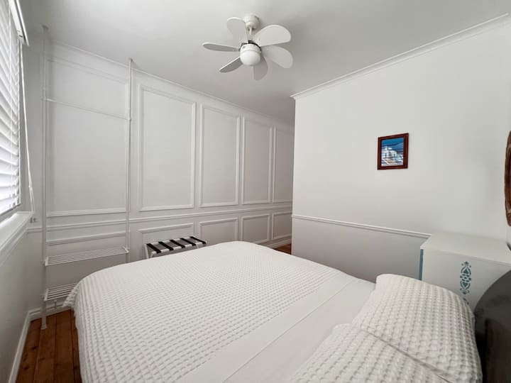 Deze lichte en gezellige kamer beschikt over een queensize bed, een verplaatsbaar bureau (op aanvraag), een ladekast, een kledingrek, een minikoelkast en een ventilator, en biedt een perfecte mix van comfort en functionaliteit voor zowel werk als ontspanning.