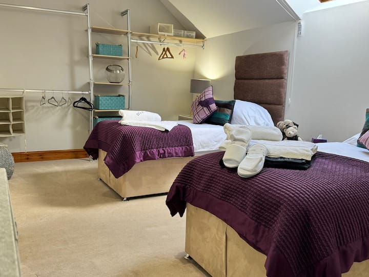 A spacious room featuring two single beds dressed in high thread count bedding.