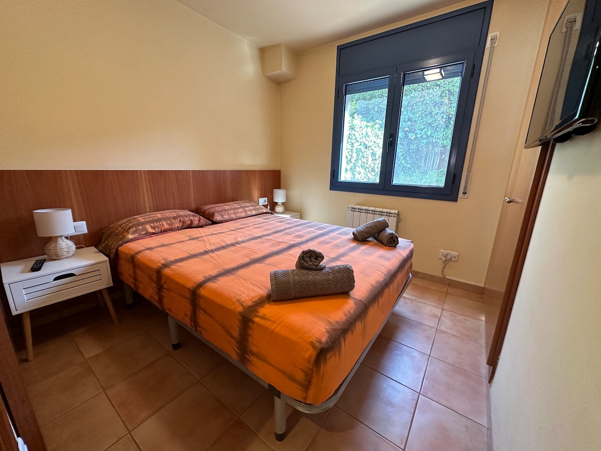 Slaapkamer op de begane grond met tweepersoonsbed, traploze toegang, achtertuinraam en tv. Direct naast badkamer 2, met douche.