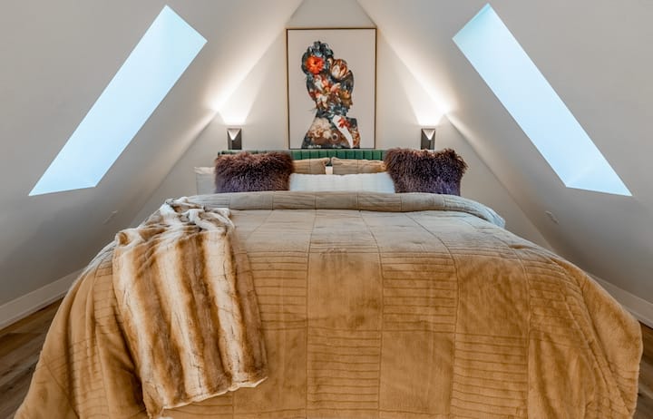 Mirna spavaća soba u potkrovlju sa stropnim prozorima, nježnim teksturama i mirnom, privlačnom atmosferom.