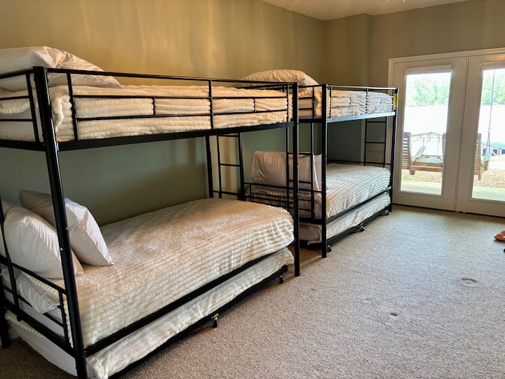 Dormitorio #4  DOS literas con ruedas debajo de cada una para un total de 6 camas de tamaño doble con acceso al patio con columpio privado con vistas al lago.  Se comparte el baño completo en el sótano.