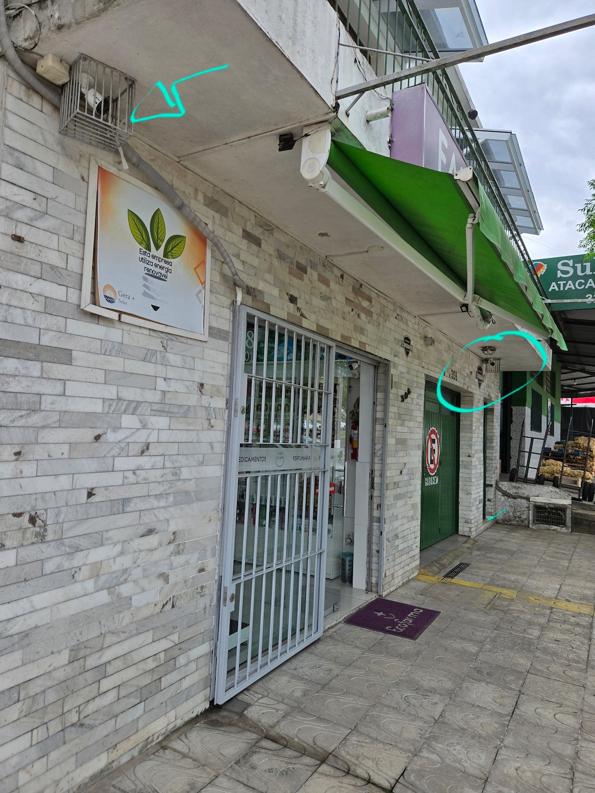 The image shows the exterior of a commercial building featuring a stone facade. A metal gate provides entry, and a sign indicating the establishment is prominently displayed on the wall. Green awnings extend above the entrance, creating a welcoming shade for visitors.