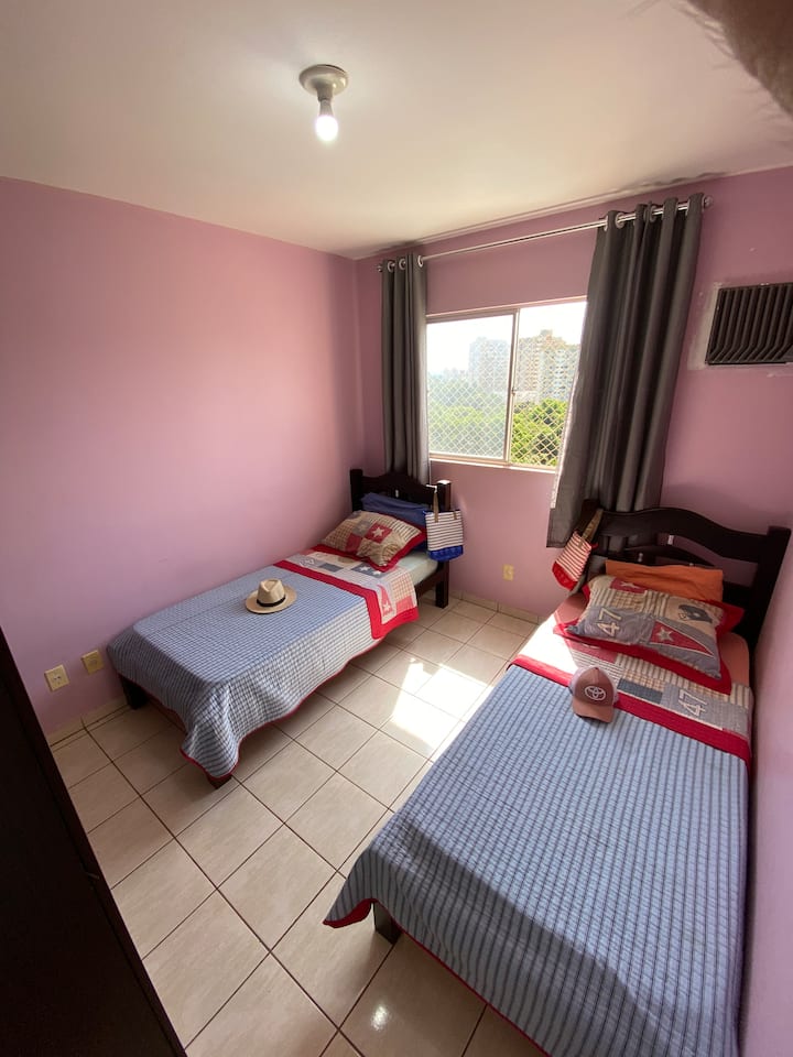 Quarto com duas camas de solteiro, ar-condicionado, cortinas e telas de proteção nas janelas, além de travesseiros e proteção nos colchões para maior conforto.