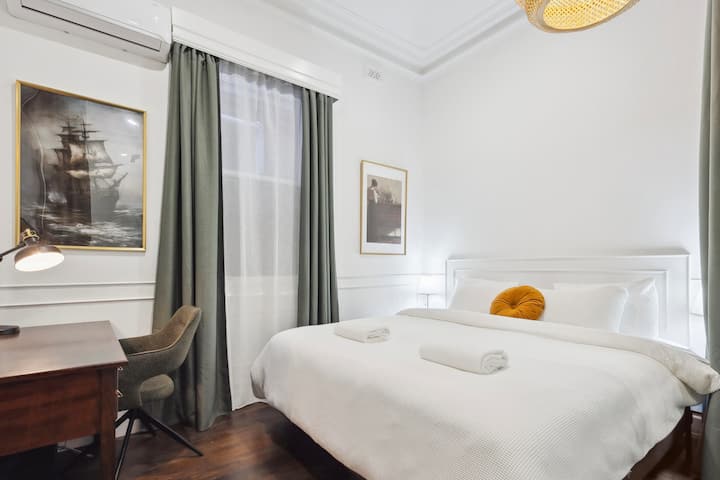Bedroom 3 has a luxurious king-sized bed with premium linen, air-conditioning, block-out curtains and soft lighting. It has ceiling-high glass walls, privacy curtains and a corner workspace. A travel cot can be placed in this room on request
