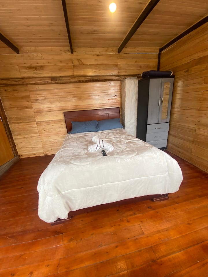 乡村风格舒适的房间，配有一张双人床、木质饰面和温馨的氛围，配有阳台，可欣赏因巴武拉和圣巴勃罗湖的美景  