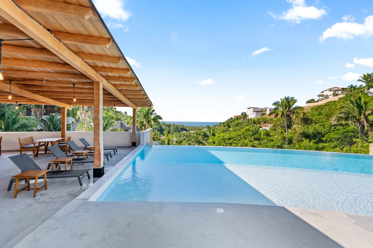 Your rooftop complex: pool on one side, covered palapa terrace on the other, green jungle hills and ocean horizon all around.