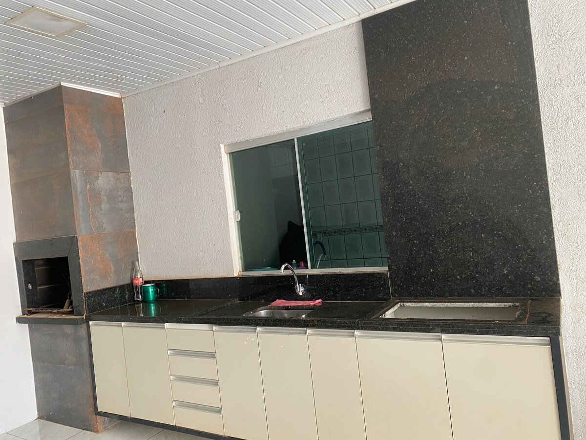 The kitchen features a modern layout with sleek cabinetry and dark granite countertops. A window offers natural light and a view of the outdoor area. A built-in grill is positioned to one side, providing an inviting space for meal preparation.