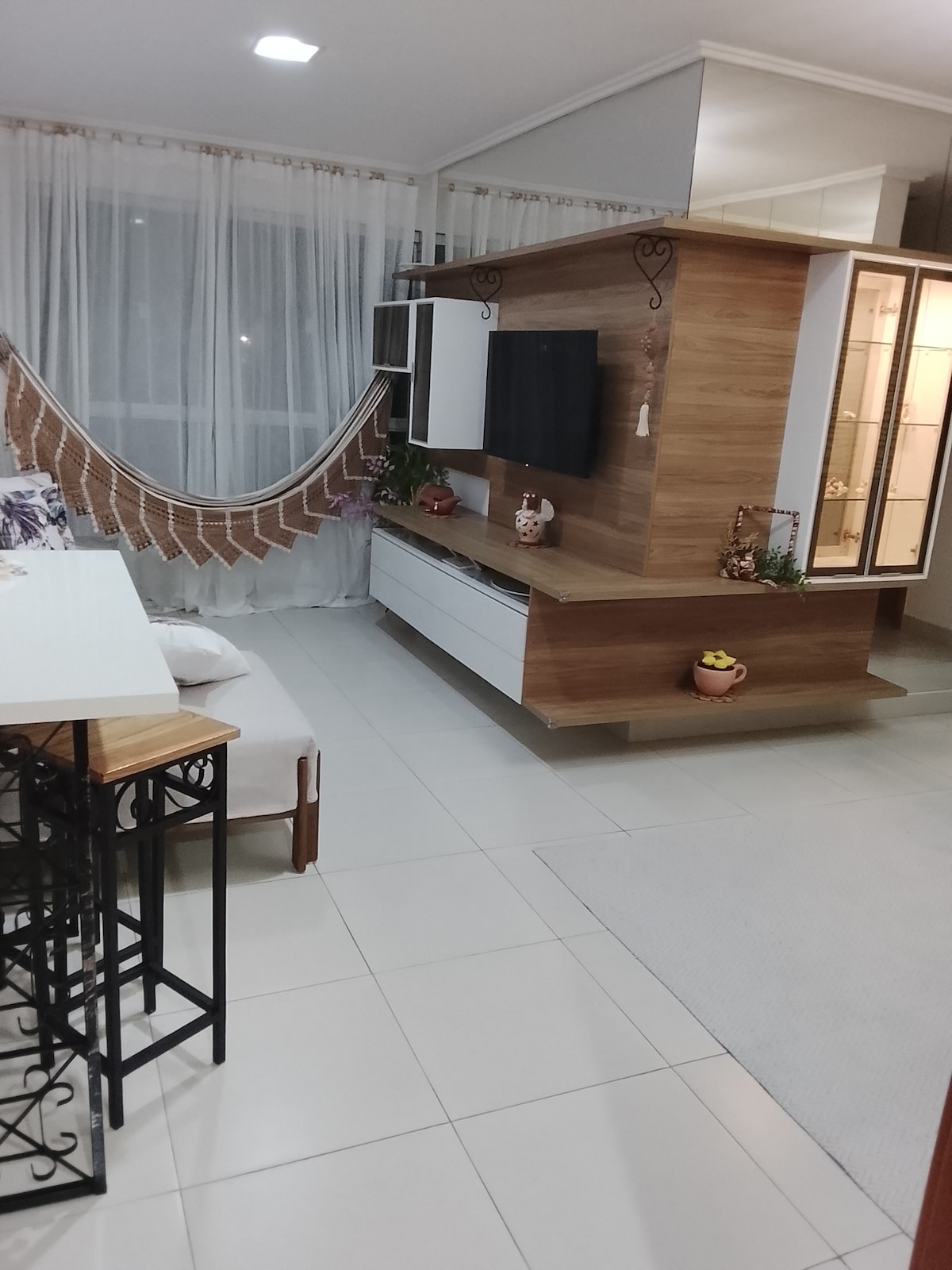 غرفة معيشة بتلفزيون وأرجوحة شبكية وبار وطاولة.