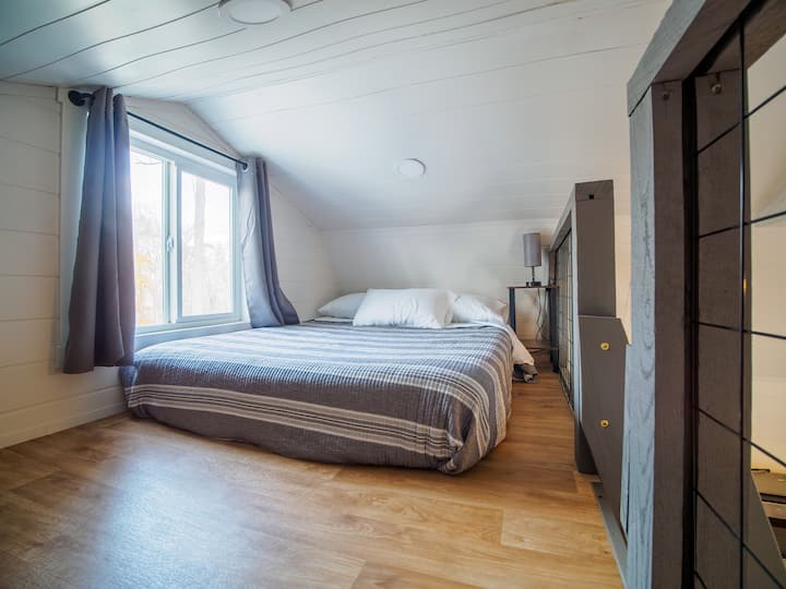 Წინა საძილე ლოფტი, რომელშიც არის ორადგილიანი საწოლი, ჩამუქებული განათება და სათანადო იატაკი ბარგისა და ნივთებისთვის.