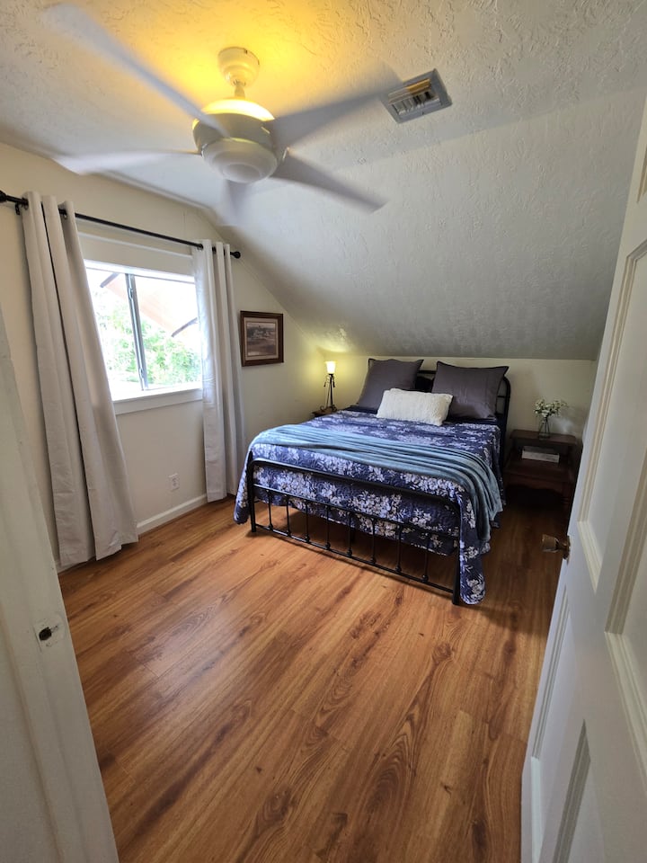 Тази спалня е първата стая вляво, когато влезете през входната врата. Гледката от прозореца е към задната пасище и горната веранда.