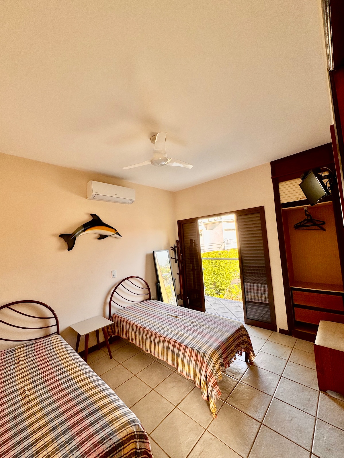 Suite con aire acondicionado, dos camas individuales, ventilador de techo, TV, balcón y armario. Está en el piso de arriba de la casa.