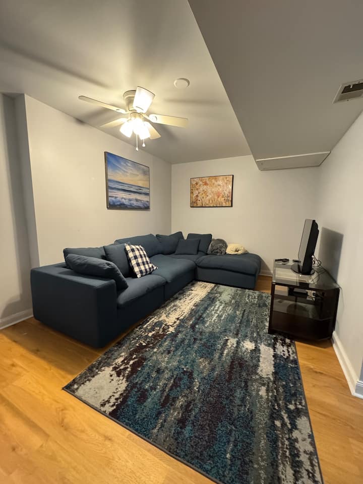 On lower level adjacent to workspace with couch, TV, & DVD player. Space for BYO air mattress if needed. 