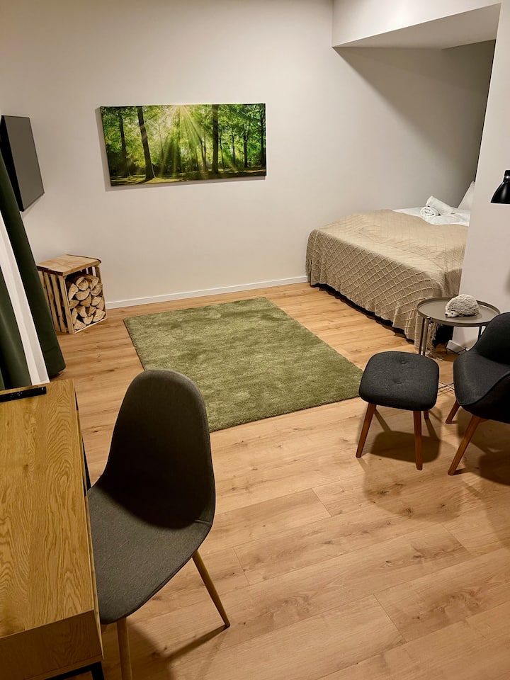 Acogedor dormitorio para dos personas en el sótano con espacio de trabajo y acogedora silla de lectura