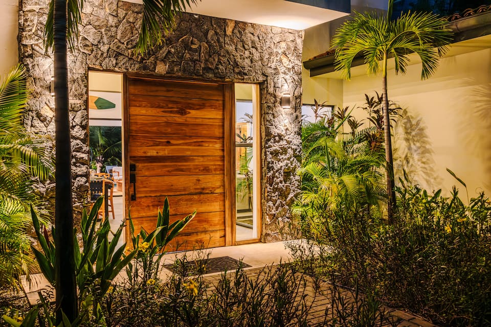 The wooden front door at dusk, the garden lit
