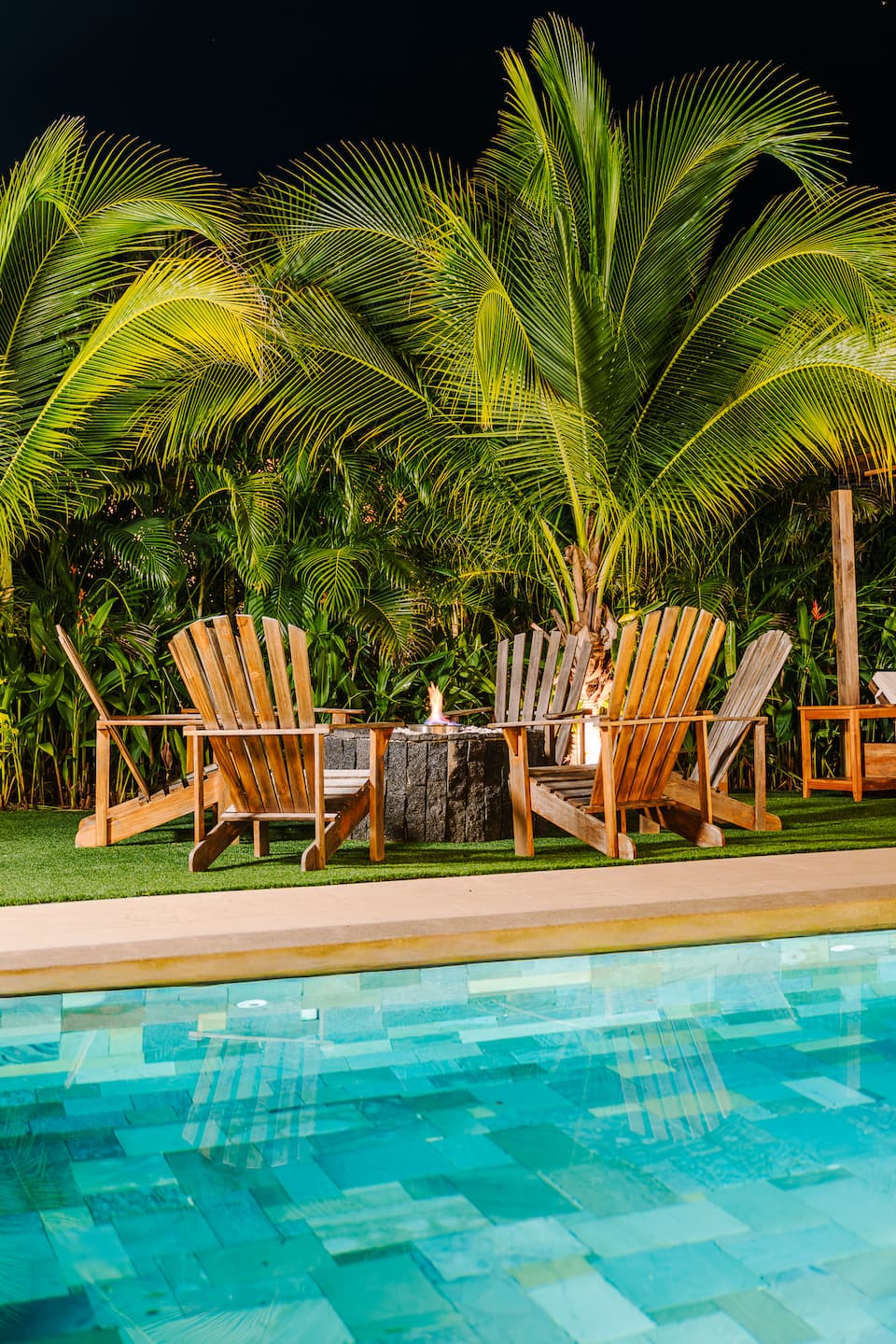 Wooden chairs around the fire pit by the pool at dusk