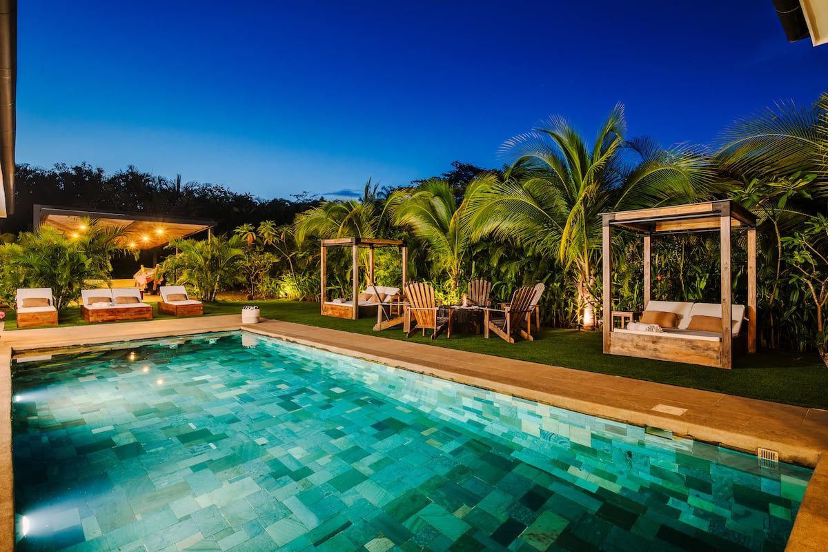 The pool at dusk, its cabanas lit