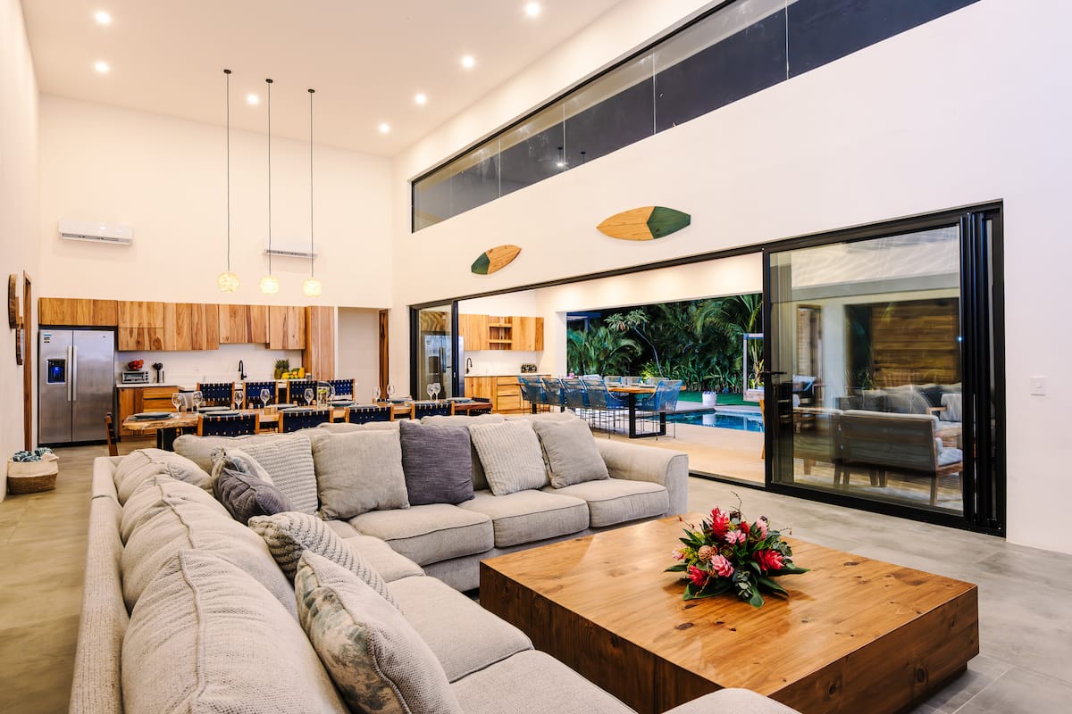 The living room under a high ceiling, sliding doors open to the garden