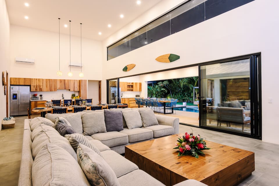 The living room under a high ceiling, sliding doors open to the garden