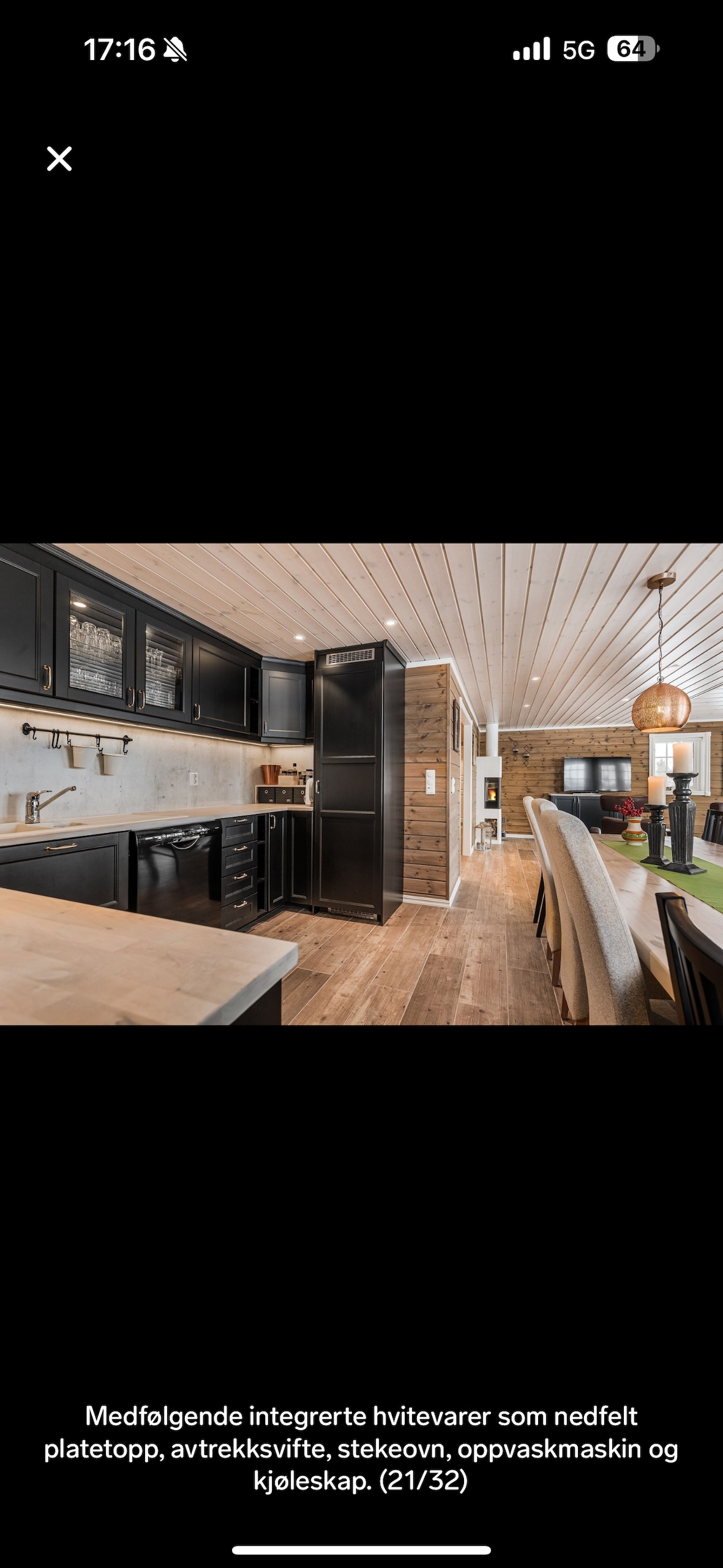 The kitchen area is showcased with modern black cabinetry, complemented by a light-colored countertop. Integrated appliances include a stovetop, range hood, oven, dishwasher, and refrigerator. A dining area with seating is visible in the background, enhancing the open-concept layout.