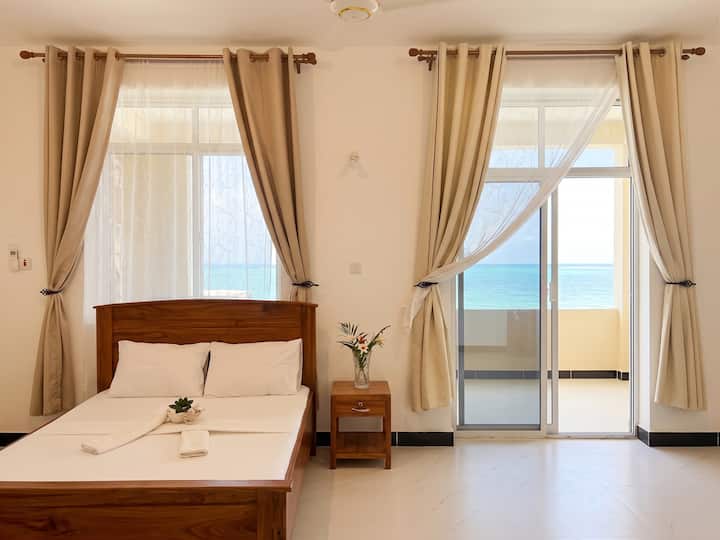 Habitación luminosa de 2 dormitorios con baño, una cómoda cama de madera, sábanas blancas impecables y una decoración acogedora. Incluye aire acondicionado, ventanas grandes y un balcón privado con vistas al mar. Un espacio tranquilo y relajante, lleno de luz natural y comodidades modernas. ✨