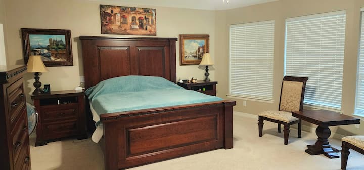Dormitorio principal con dos cajoneras, mesas auxiliares y sillas de estar