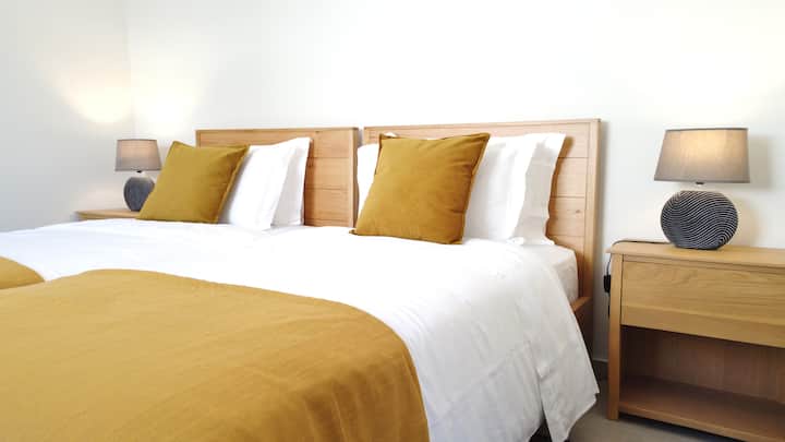 2 camas individuales, almohadas adicionales, armario y cortinas opacas. Espacio de trabajo exclusivo con escritorio elevador Steelcase Gesture y silla ergonómica.