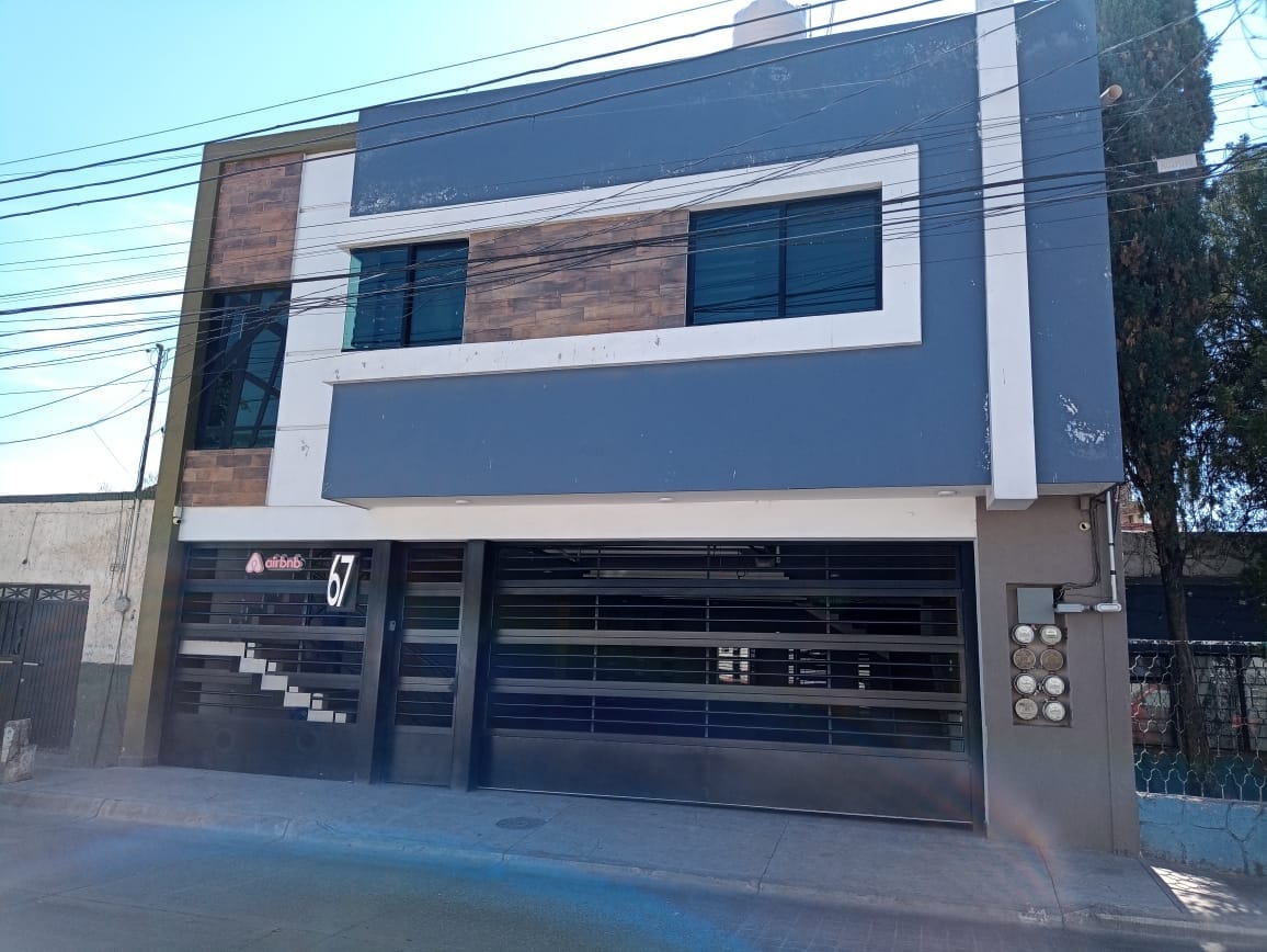The modern building features a well-maintained exterior with a combination of gray and wooden accents. Large windows allow natural light to enter, while the spacious garage is equipped with automatic doors, providing convenient access for vehicles.