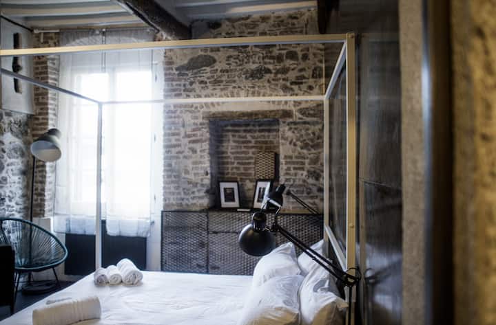 Dormitorio de diseño industrial con paredes de piedra vista, cómoda cama doble y ambiente relajante para un descanso perfecto.