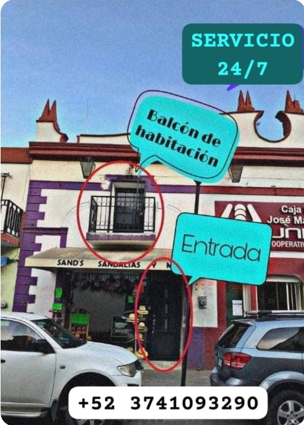 The exterior of a two-story building is shown, featuring a balcony above the entryway. A sign indicating 24/7 service is displayed prominently. The bottom level includes signage for local businesses, and vehicles are parked along the street, indicating a busy area.