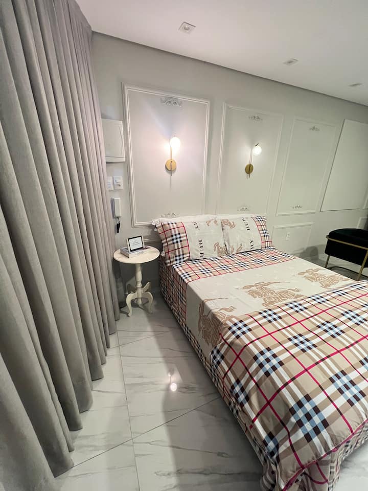 Comfortabele slaapkamer in Loft 02, met een tweepersoonsbed, beddengoed, gezellige verlichting en een gordijn voor meer privacy. Accommodatie in Gaspar voor wie op zoek is naar Fazzenda Park, Morro do Cachorro, deltavliegen, paragliden, raften, grotten en wandelpaden.