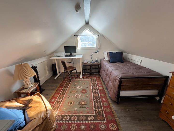 ლოფტი (ბლოკი 2) სამუშაო სივრცით, პარკისებრი სავარძლით, კომოდითა და ერთადგილიანი საწოლით, რომლის ქვეშაც დამატებითი საწოლია.