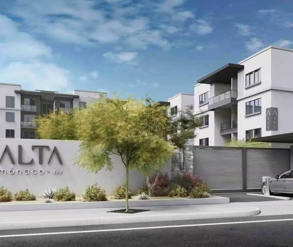 An inviting exterior view of a modern apartment complex is depicted, featuring a prominent sign with the name 'ALTA.' Surrounding greenery and well-maintained landscaping enhance the entrance. The design showcases a contemporary architectural style, with multiple levels and balconies visible.